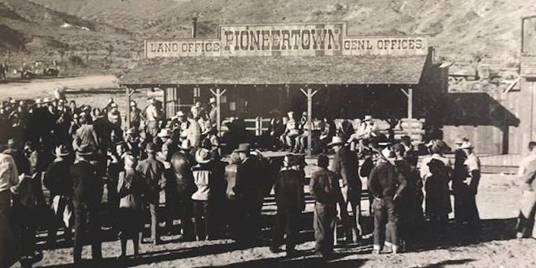 Crowd of people at the Land Office image. links to news articles about land development in Pioneertown.